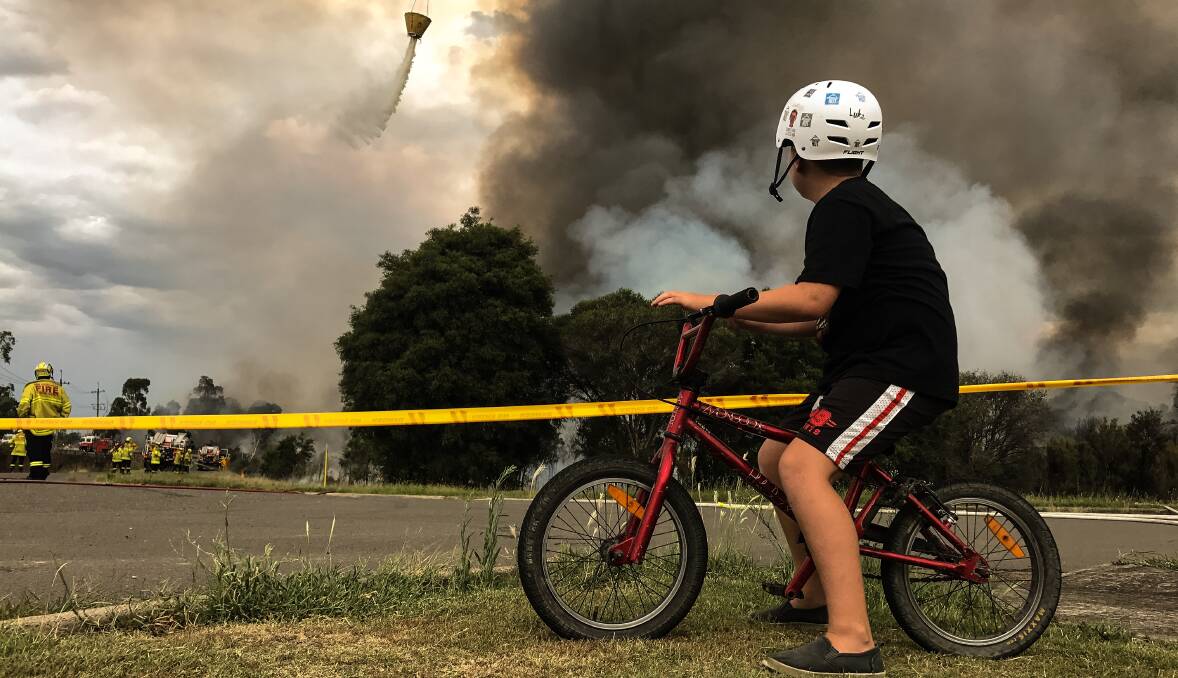 CONCERN: Luke Dietrich, 11, from nearby Appleton Road, watches from relative safety as plumes of smoke rise from the deliberately-lit bushfire near Kurri Kurri. Pictures: Marina Neil.