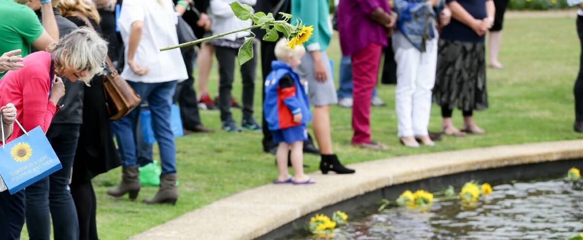 MEMORIAL: Attendees throw sunflowers into the water at Foreshore Park during the annual Wesley LifeForce Memorial Day in hope and remembrance. Picture: Ryan Osland