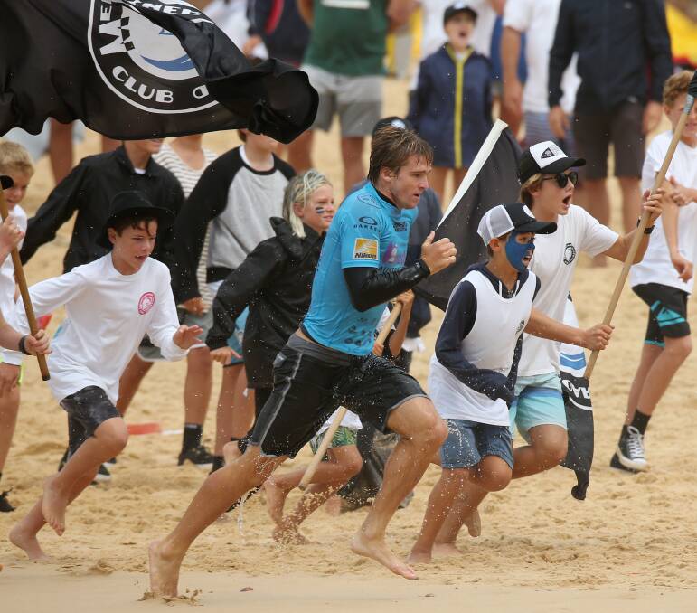 Ryan Callinan sprints up the beach with a throng of Merewether Boardriders Club supporters in tow.