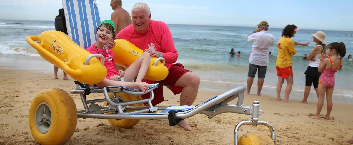 INCLUSION: Nine-year-old Amelia Musgrave with Cooks Hill Surf Club's John Mayo. The club has two new floating wheelchairs to help people with a disability access the beach and surf. Picture: Marina Neil