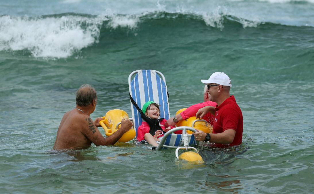 ENJOYMENT: Nine-year-old Amelia Musgrave with regional director of Variety - The Children's Charity Jason Burke (red shirt) and Cooks Hill SLSC lifeguards John Mayo (pink shirt) and Terry 'The Godfather' Cosgrove (no shirt). Picture: Marina Neil