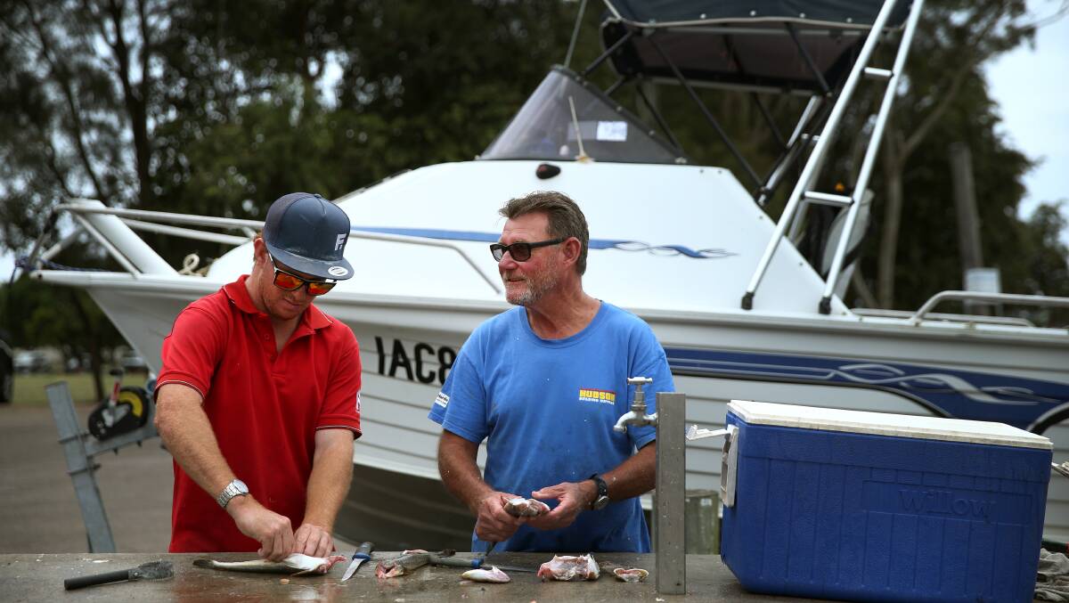 STAYING DRY: Neal Redriff, cleaning fish with his son James, said as a safety precaution, he did not drink alcohol when he went on his boat. Picture: Marina Neil 