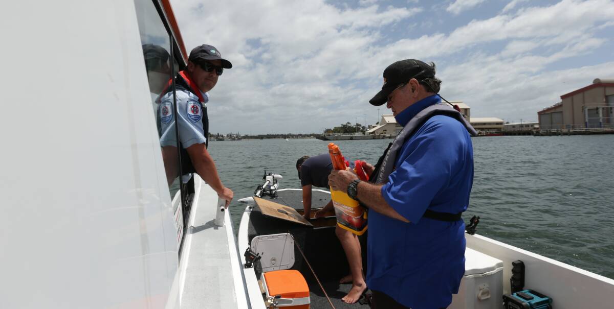 Safety Inspection: Gary Conway, of Redhead, shows Boating Safety Officer Mick Cleland a set of flares, while the skipper, Logan Conway, of Dubbo, reaches for the lifejackets. Picture: Simone De Peak