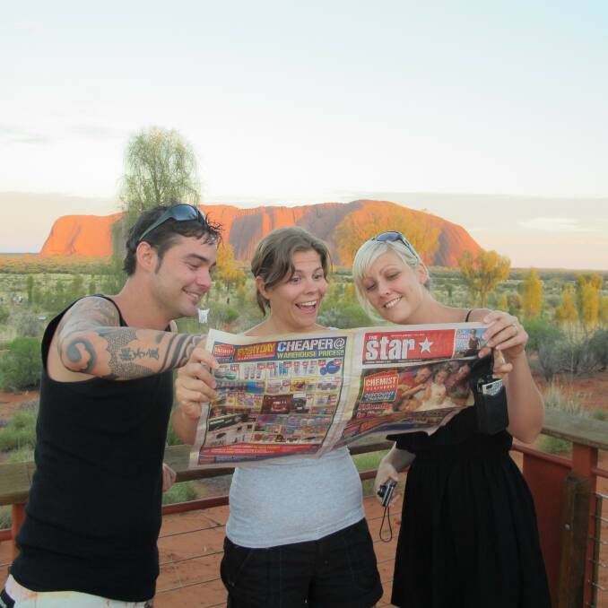 LUCKY PHOTO: Chris Plain, Sarah Morrison and Jodie Plain reading The Star at sunrise by the rock. Picture: Deano Morrison