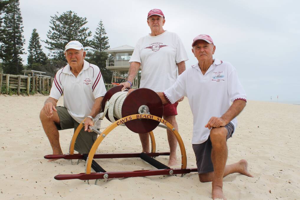 SHOULDERING ON: Caves Beach Surf Life Saving Club members Mick Ellercamp, Ron Ham and Don Ellercamp with the reel that they carry in the annual march past.