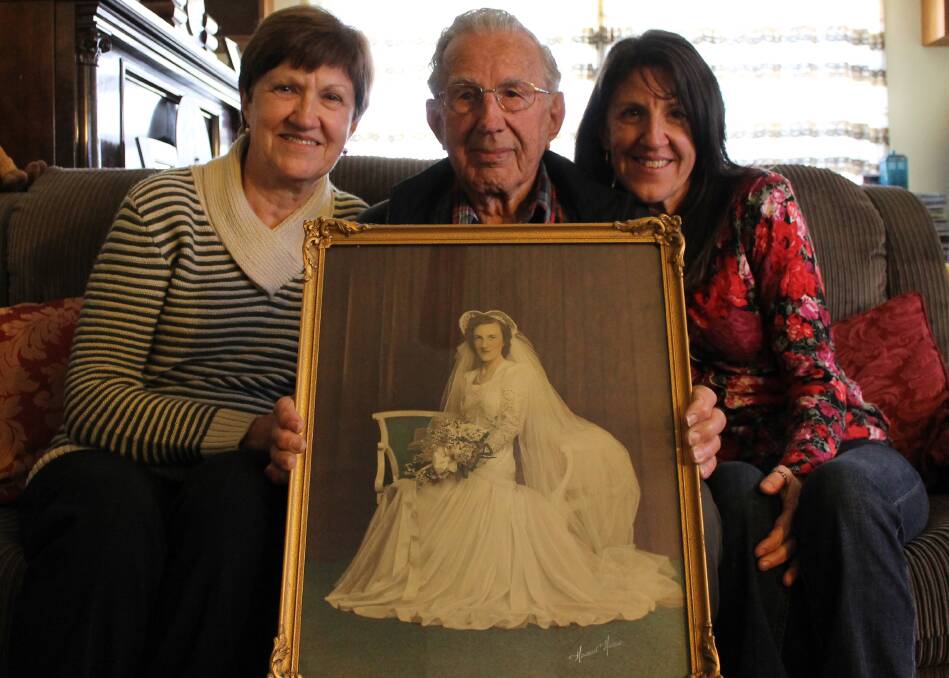 FOND MEMORIES: Sisters Lynette Prince and Leanne Hudson with their father Gordon, who holds a photograph of the day he married his late wife Dorothy.