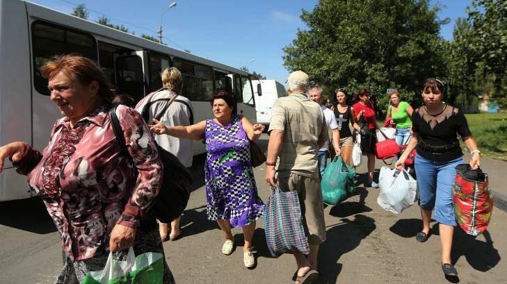 Residents of Shakhtersk run towards buses being provided by the Pro-Russian rebels for people wanting to flee the town from the conflict after heavy shelling over the past two days in the area. Photo: Kate Geraghty