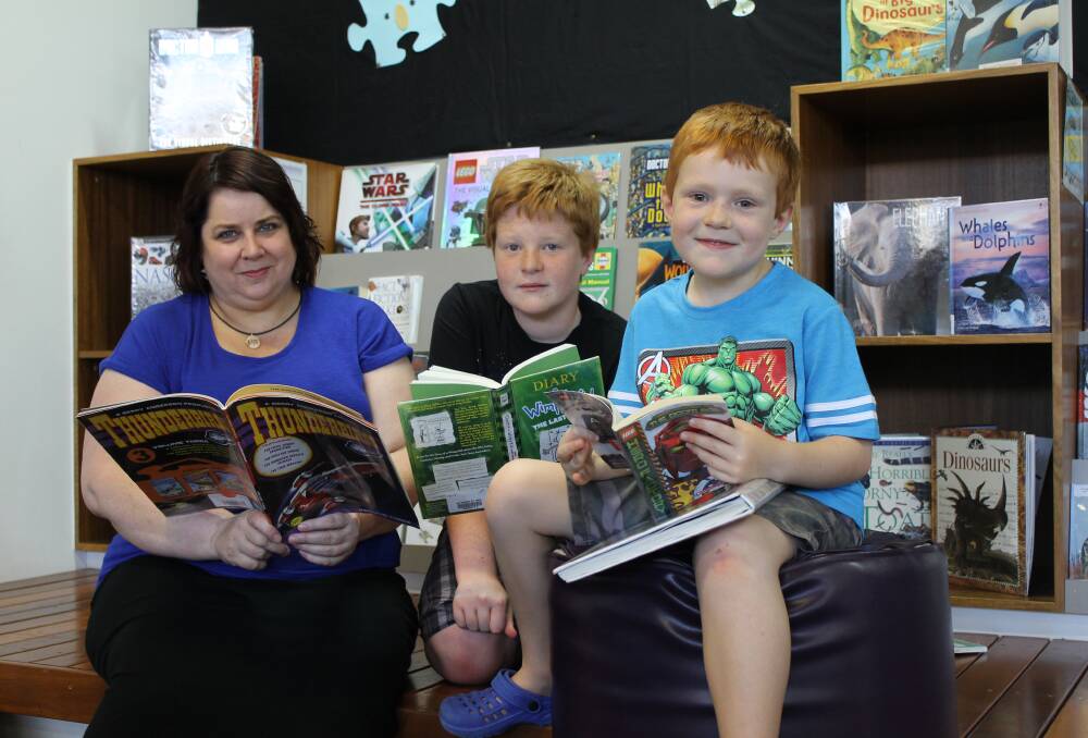 STORIES GALORE: Swansea librarian Cathy Shay reads a book with siblings and Summer Reading Program participants Gabe Mason, 13, and Petey Smith, 6, of Caves Beach.
