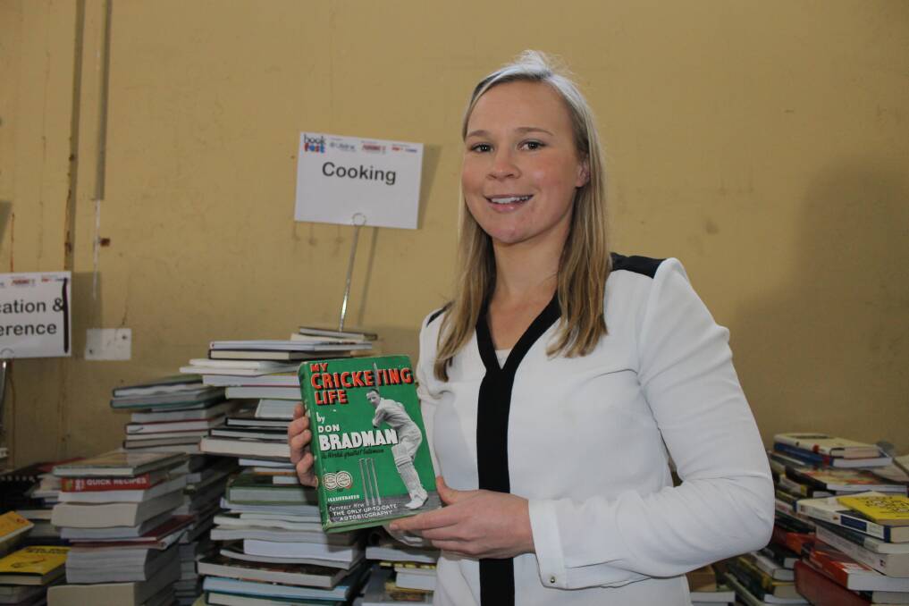 Lifeline Newcastle and Hunter public relations manager Emma Askew with a copy of My Cricketing Life by Don Bradman.