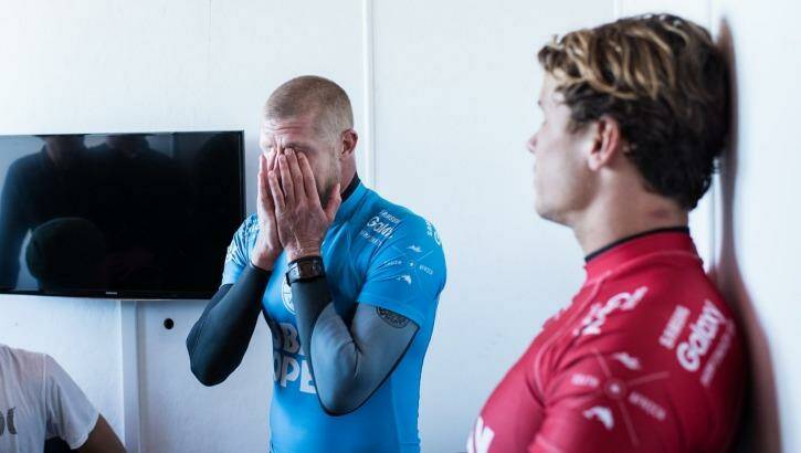 Mick Fanning of Australia (in blue) holds his head in his hands in disbelief after being attacked by a shark during the final of the JBay Open while fellow finalist Julian Wilson (red) looks on. Photo: WSL/Kirstin Cestari