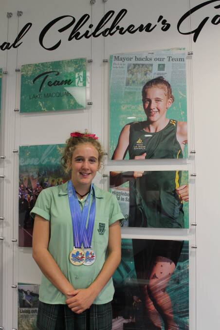Track and field athlete Isobel Warby stands beside her photo at the International Children's Games exhibition.
