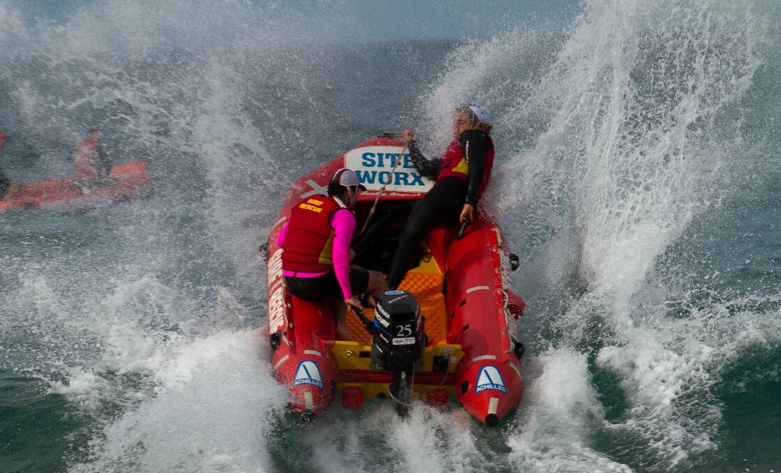 The Caves Beach inflatable boat rescue team takes on the surf. Picture: Louis Tassone