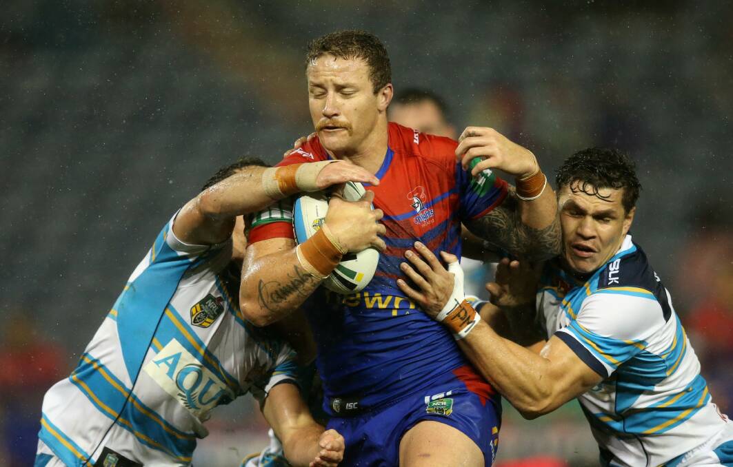 The Newcastle Knights’ Korbin Sims pushes past Gold Coast Titans defence to score a try.