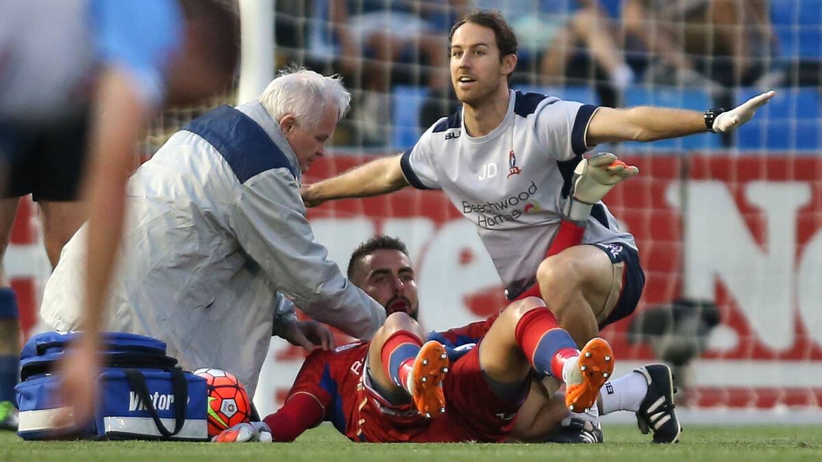 GAME OVER: The Newcastle Jets’ Mark Birighitti receives attention for his serious injury. Picture: Getty Images