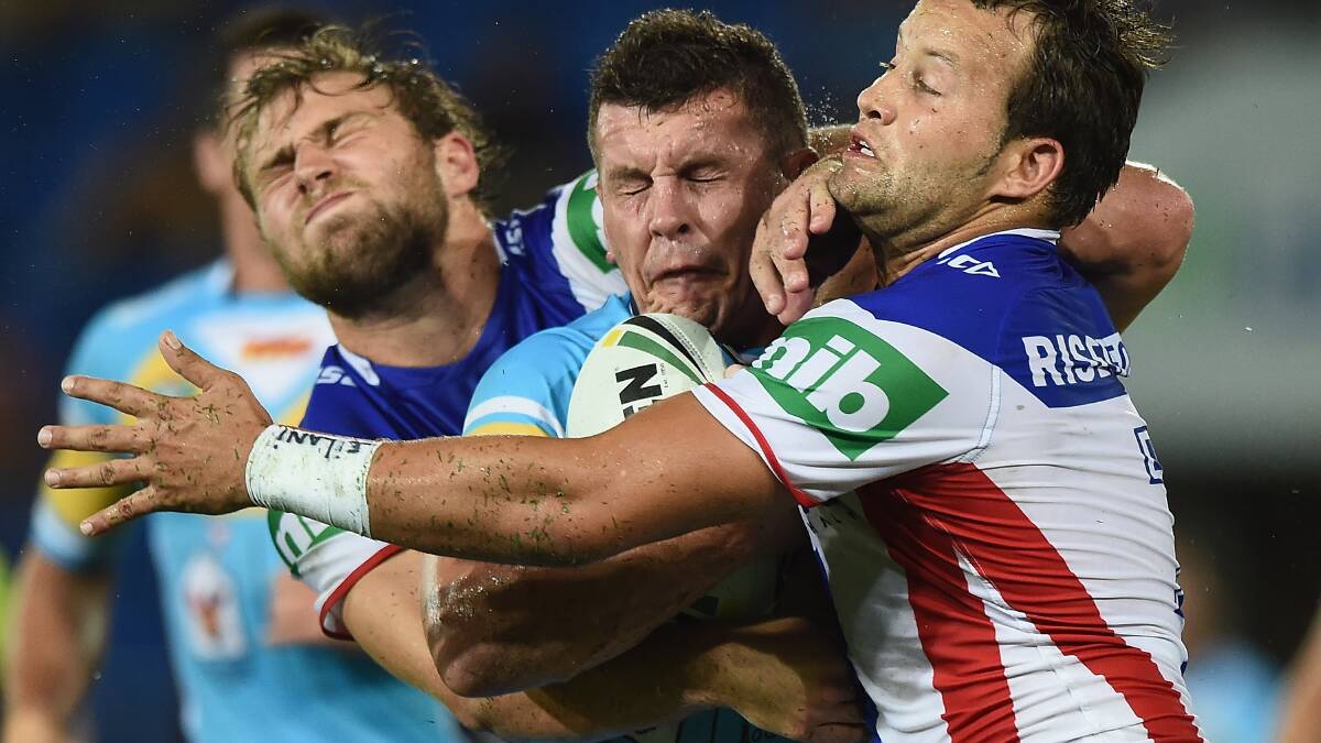 Greg Bird of the Titans is tackled by Robbie Rochow and Tyrone Roberts (R) of the Knights during the round three NRL match between the Gold Coast Titans and the Newcastle Knights at Cbus Super Stadium on March 22, 2015 on the Gold Coast, Australia. (Photo by Matt Roberts/Getty Images)