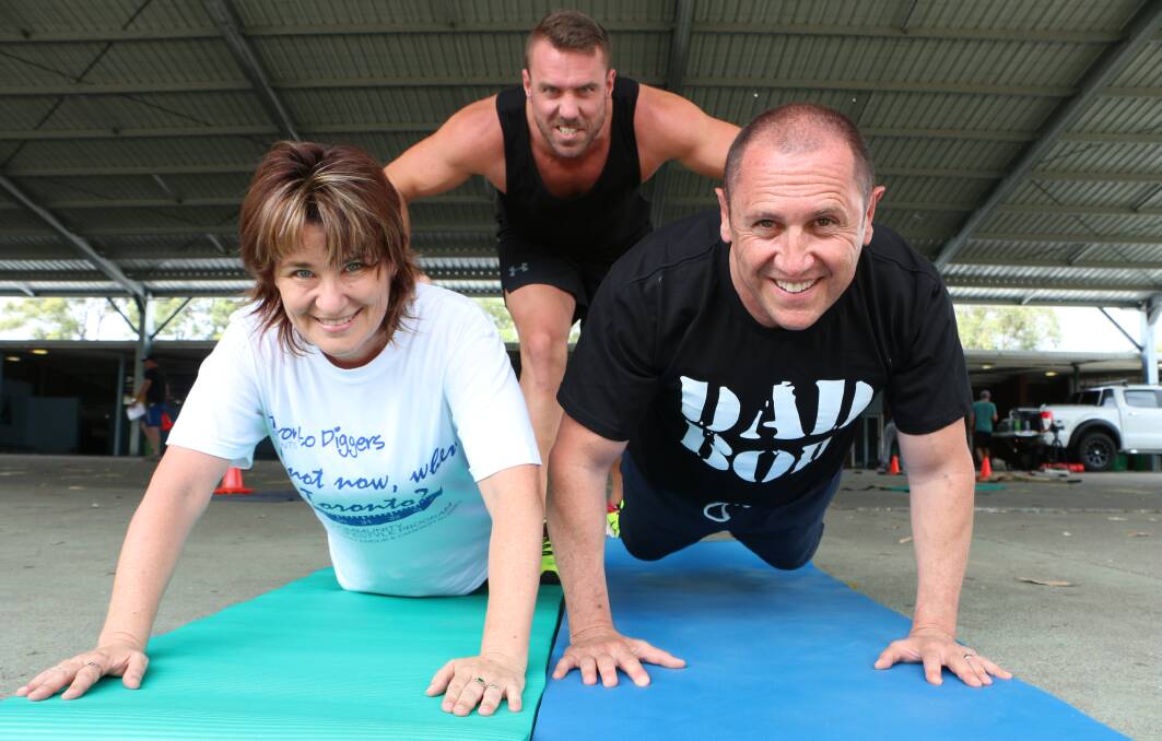 PUSH IT: Personal trainer Cameron Byrnes drives Cathy Handcock and Larry Emdur at the Toronto boot camp this morning. Picture: David Stewart
