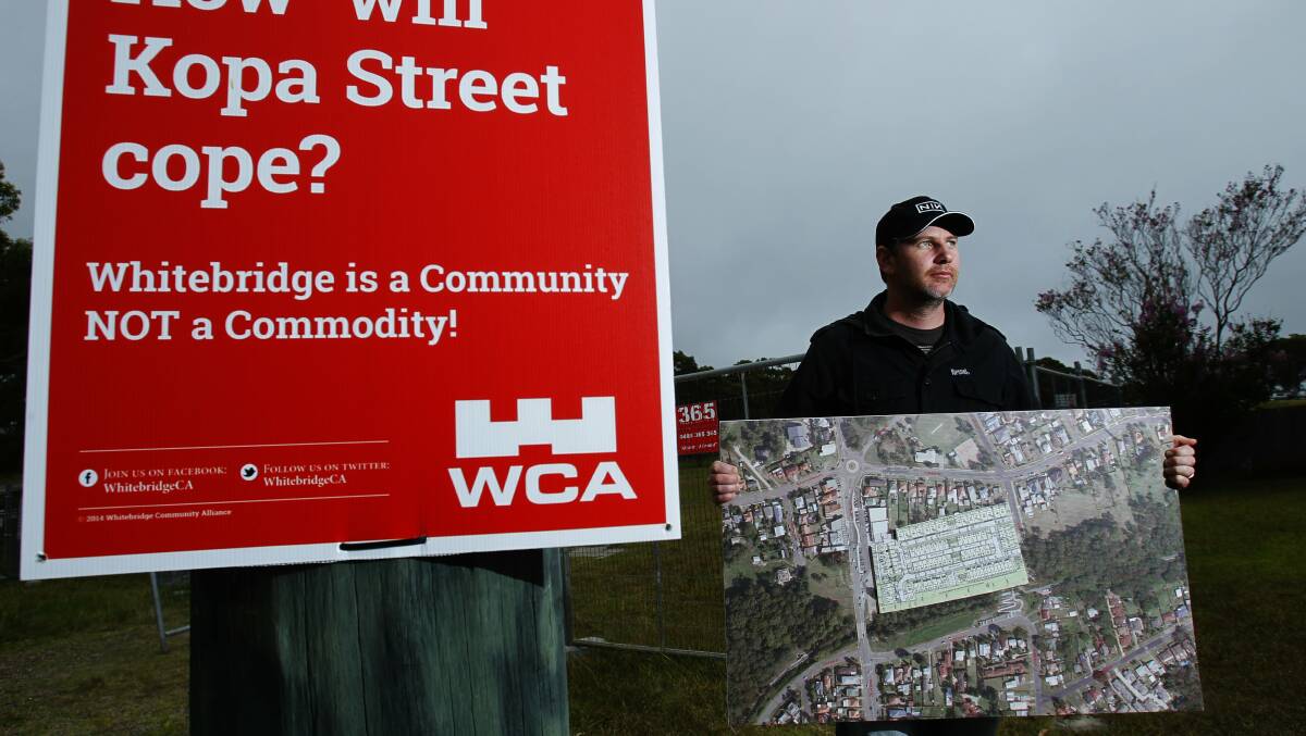 Whitebridge resident Sean Brown is spokesperson for Whitebridge Community Alliance who are opposing a development on Kopa Street, Whitebridge. Pictured at the site of the development with a WCA sign saying Whitebridge is a Community NOT a Commodity and holding an aerial photo of the area with the proposed development superimposed.