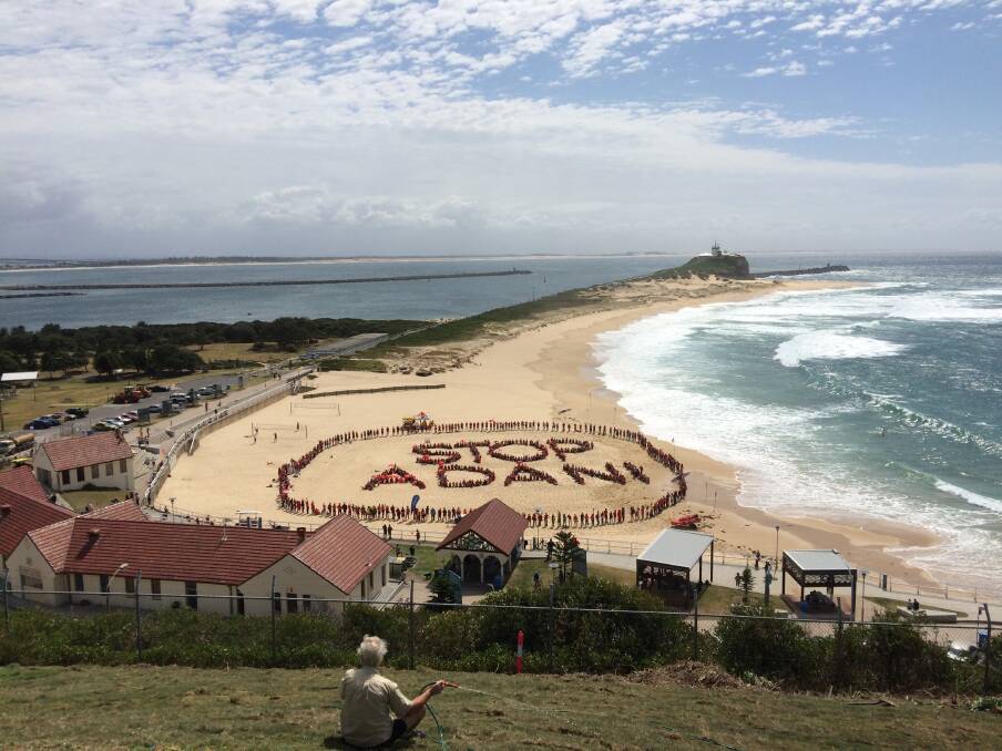 ACTION: People form a human billboard at Nobbys Beach in Newcastle as part of the national day of action to "Stop Adani". Picture: Ryan Jago 