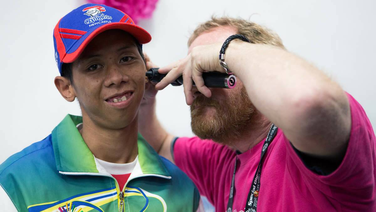 HOLD STILL: A Newcastle clinician performs a hearing check on a Special Olympics 2013 Asia Pacific Games athlete.Picture: Newcastle Sundance photographer Stuart Hazell.