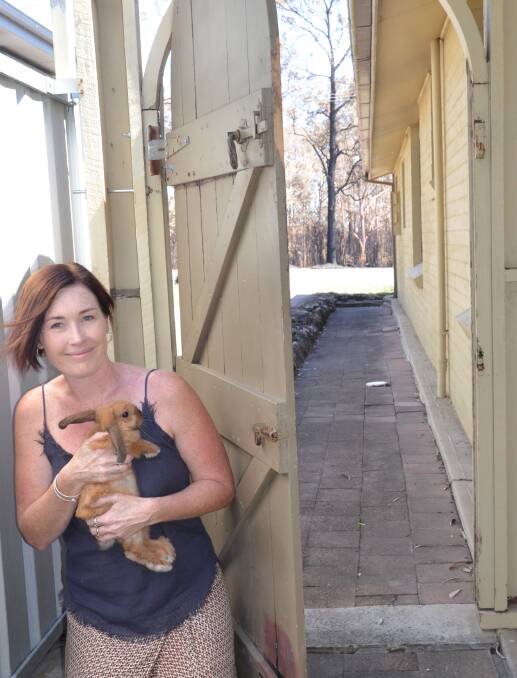 CLOSE CALL: Jillian Loux and her rabbit Boo at the gate that was scorched by embers from the bushfire in Kurri Kurri last week. Picture: Krystal Sellars