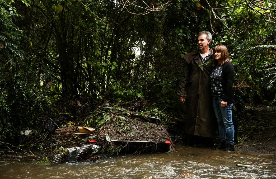 Blockage: Susan and Greg Foster near a submerged shopping trolley in Scrubby Creek. Dozens of trolleys are strewn along the creek bank. Picture: Marina Neil 