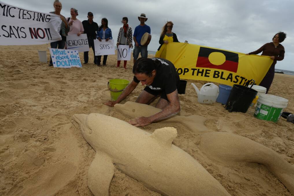 Sand sculptor Dennis Massoud building dolphins at Nobbys Beach, in protest of the seismic testing underway off the coast. 