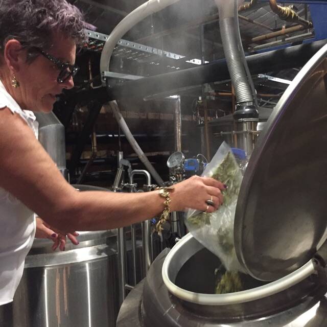 NEW ROLE: Carrington Bowling Club chief executive officer Jaci Lappin adds hops she grew on site to a kettle at Foghorn Brewhouse. 