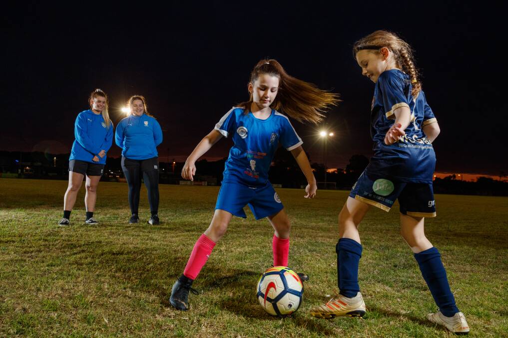 ON THE BALL: New Lambton captains Toria Campbell and Lisa Cochrane watch on as young Eagles Ruby Thomas and Mia Sabotkovsi play. The club will hold Girls Rock Football clinics in the holidays. Picture: Max Mason-Hubers