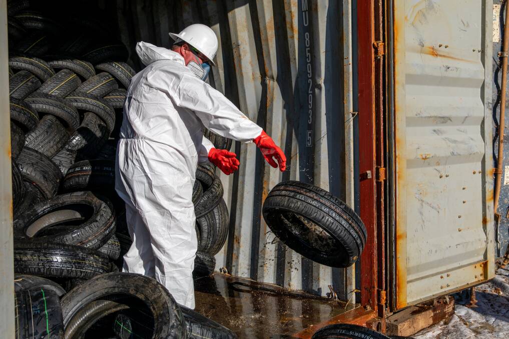 SUITED UP: A worker removes tyres from a container. 