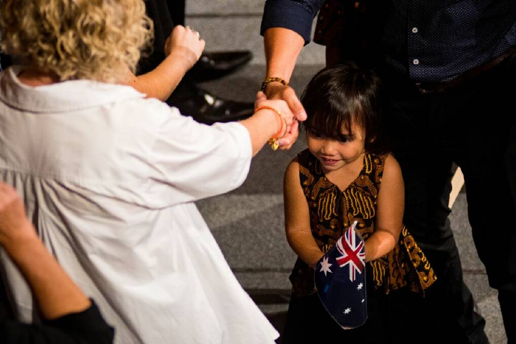 CITIZEN: MP Sharon Claydon offers an Australian flag to a young girl after she officially became an Australian citizen at a ceremony at City Hall on Saturday. Photo: Simon McCarthy