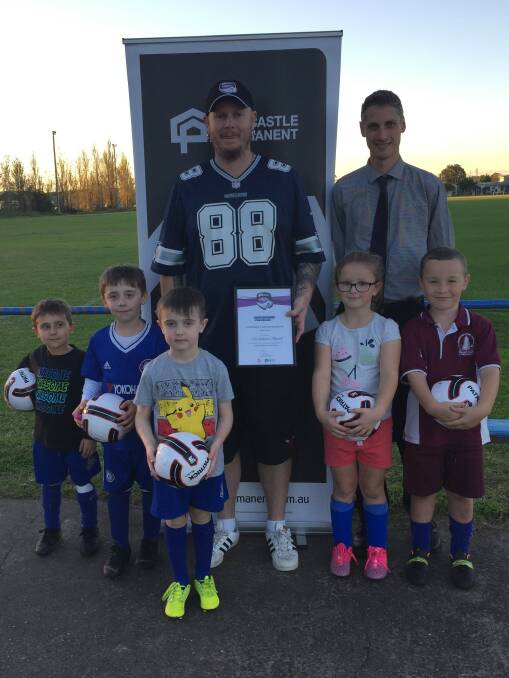 Christian Plant from Lake Macquarie FC with Newcastle Permanent representative Matt Smith and little Lake Mac footballers.