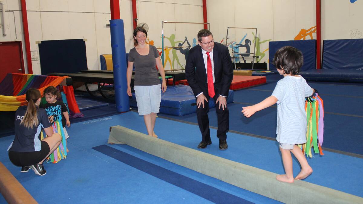 A KinderGym child shows Mr Conroy his abilities on the beam.
