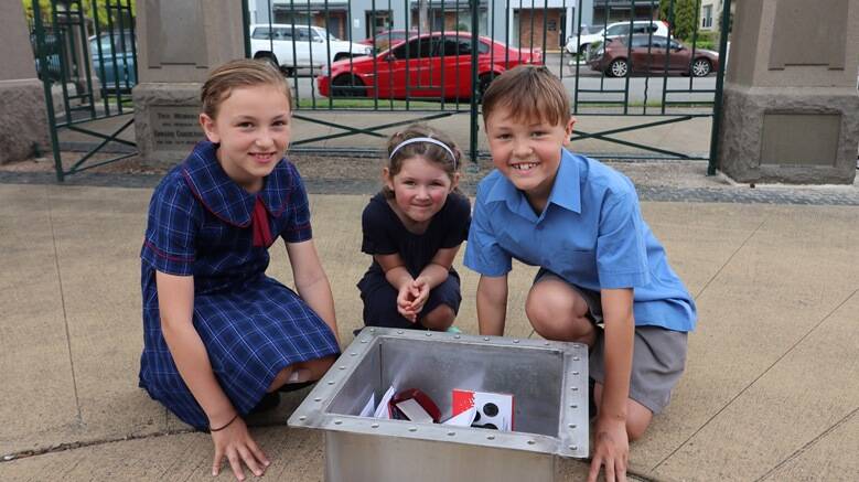 St John's Primary School students Remy Whitson, 9 and Elliot Guest, 9 with Mia Witherdin, 4 (middle) with the time capsule that will be buried in Lambton Park on Saturday, October 20. It will stay buried for 100 years.