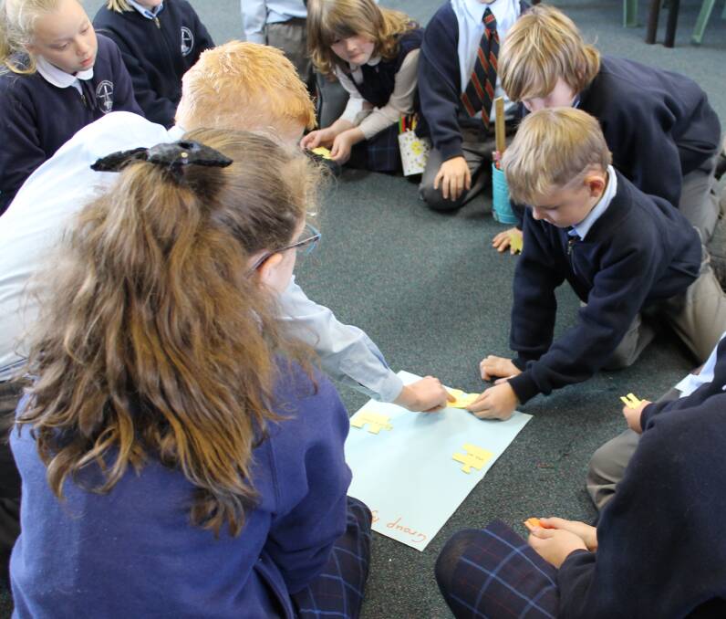 HELPING HAND: St Francis Xavier's Primary School peer support program in action as two year 6 leaders do a puzzle with other students.