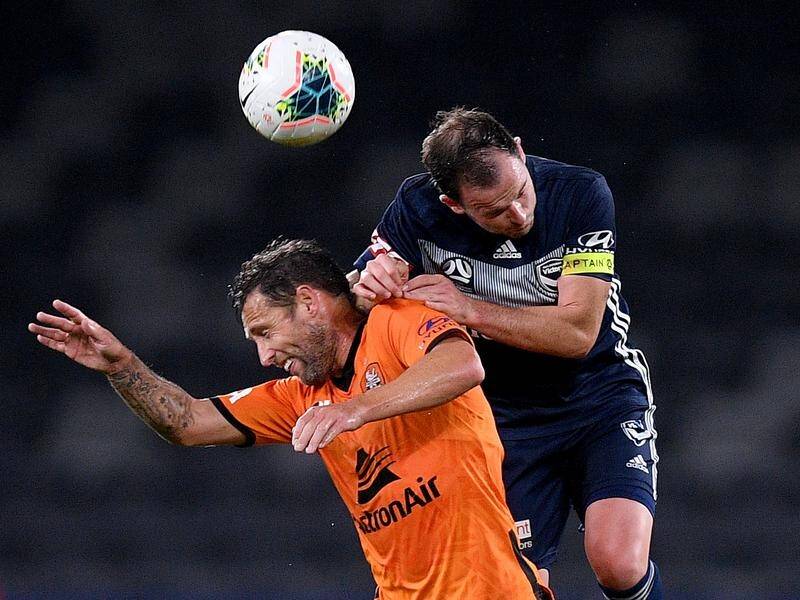 Leigh Broxham of the Victory competes to head the ball with Scott McDonald of the Roar.