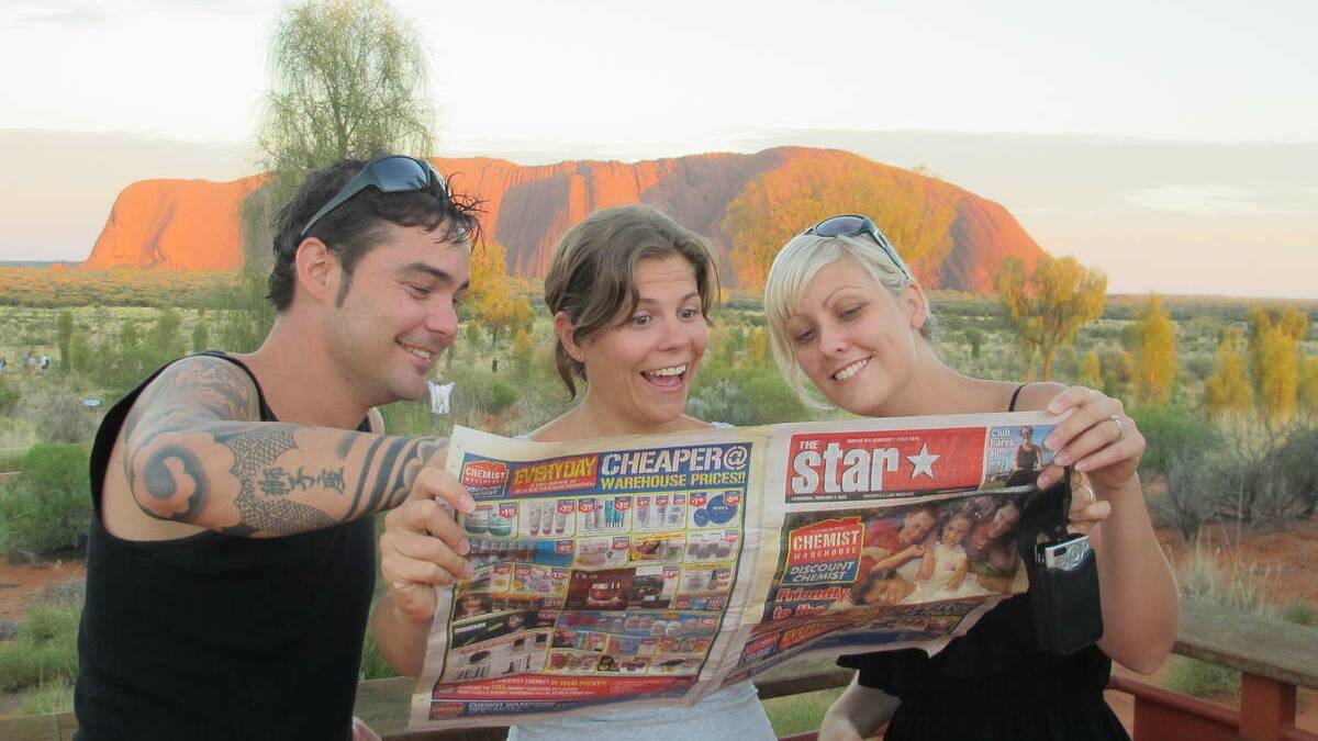 STARS: Chris Plain, Sarah Morrison and Jodie Plain reading The Star at Uluru. Picture: Deano Morrison.