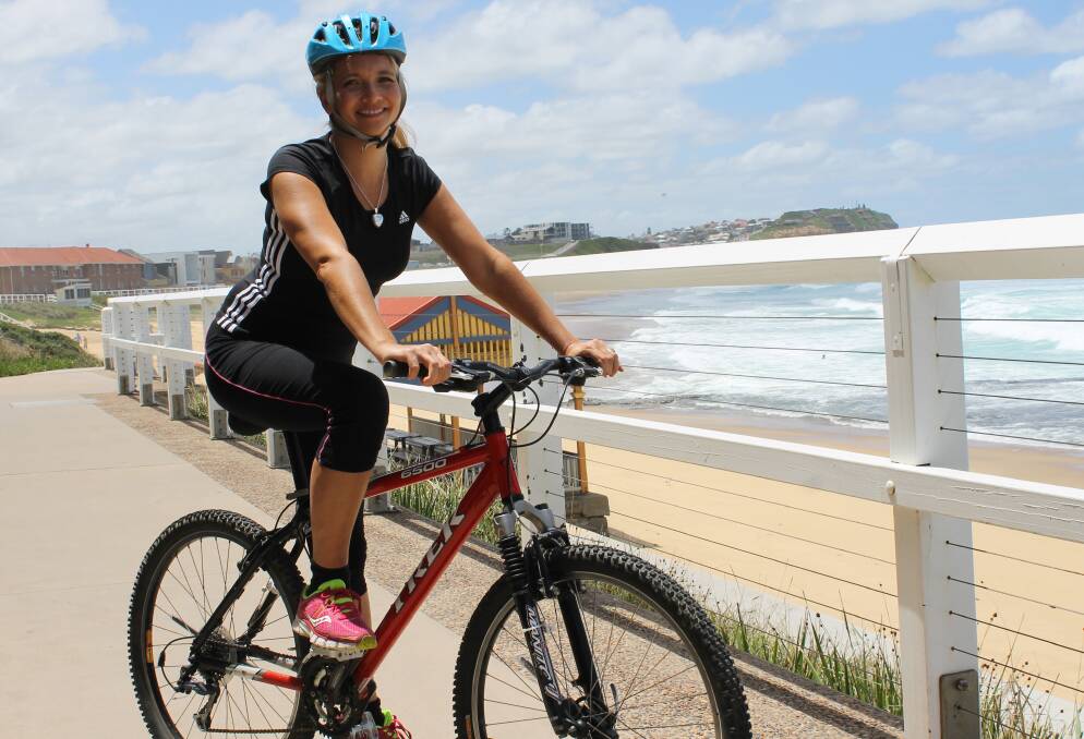 FAIR DEAL: Candace Sherriff on her bike at Merewether beach.