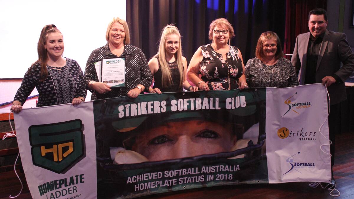 The Strikers Softball Club holds up their Homeplate banner.