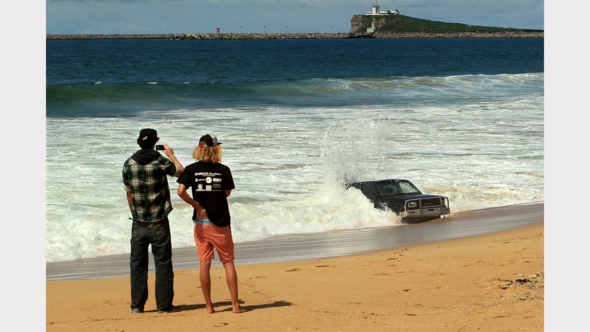 Police, towing workers and locals with the abandoned four-wheel drive on Stockton Beach on Monday afternoon. Picture: Jonathan Carroll